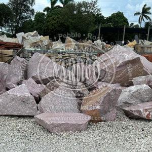Imported Red Mica Imported Boulder, a vibrant red stone with sparkling accents, perfect for contractors and homeowners to enhance outdoor spaces